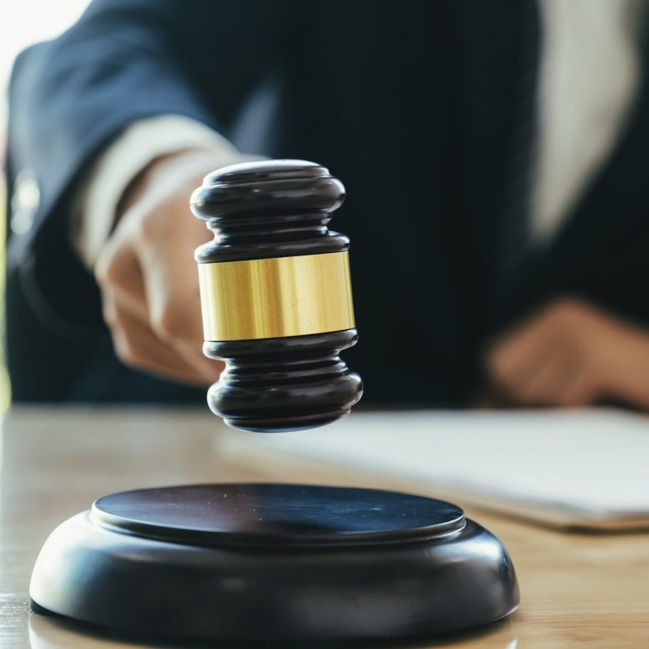 Vollgutachten Ein Richterhammer, der über einem Holztisch schwebt.