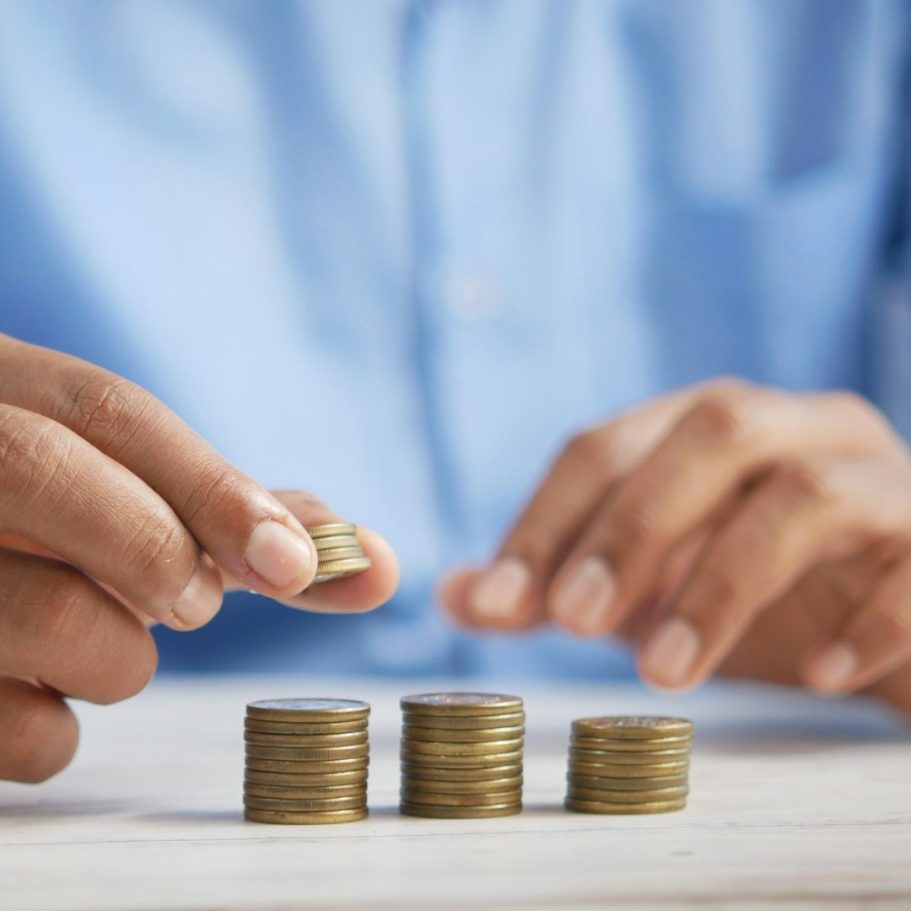 Kaufpreisaufteilung Eine Hand stapelt Münzen auf einem Tisch.